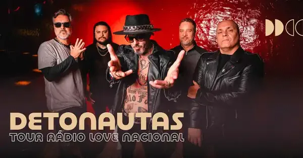 Banda Detonautas em show em São Paulo. Membros no palco com instrumentos sob iluminação de palco.
